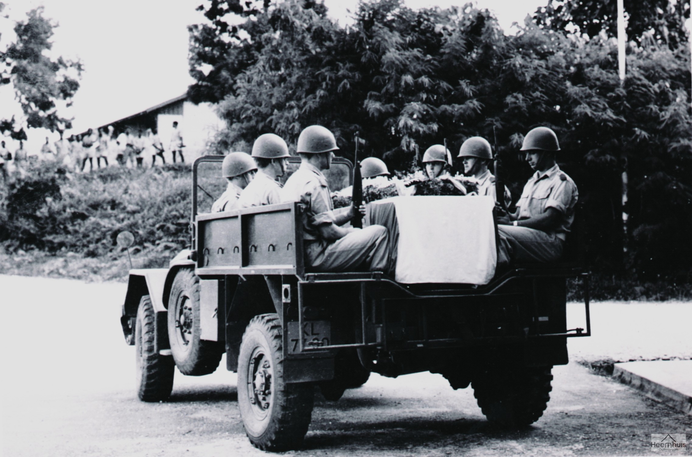 Henk Oude Luttikhuis in Nieuw Guinea met zijn kameraden rond de kist van hun verongelukte luitenant.